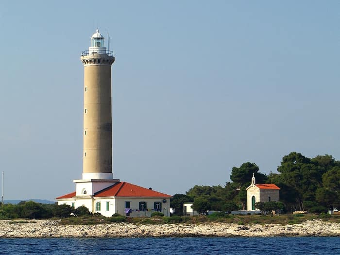 Veli Rat Lighthouse with its white tower and yellow keeper's house on Dugi Otok